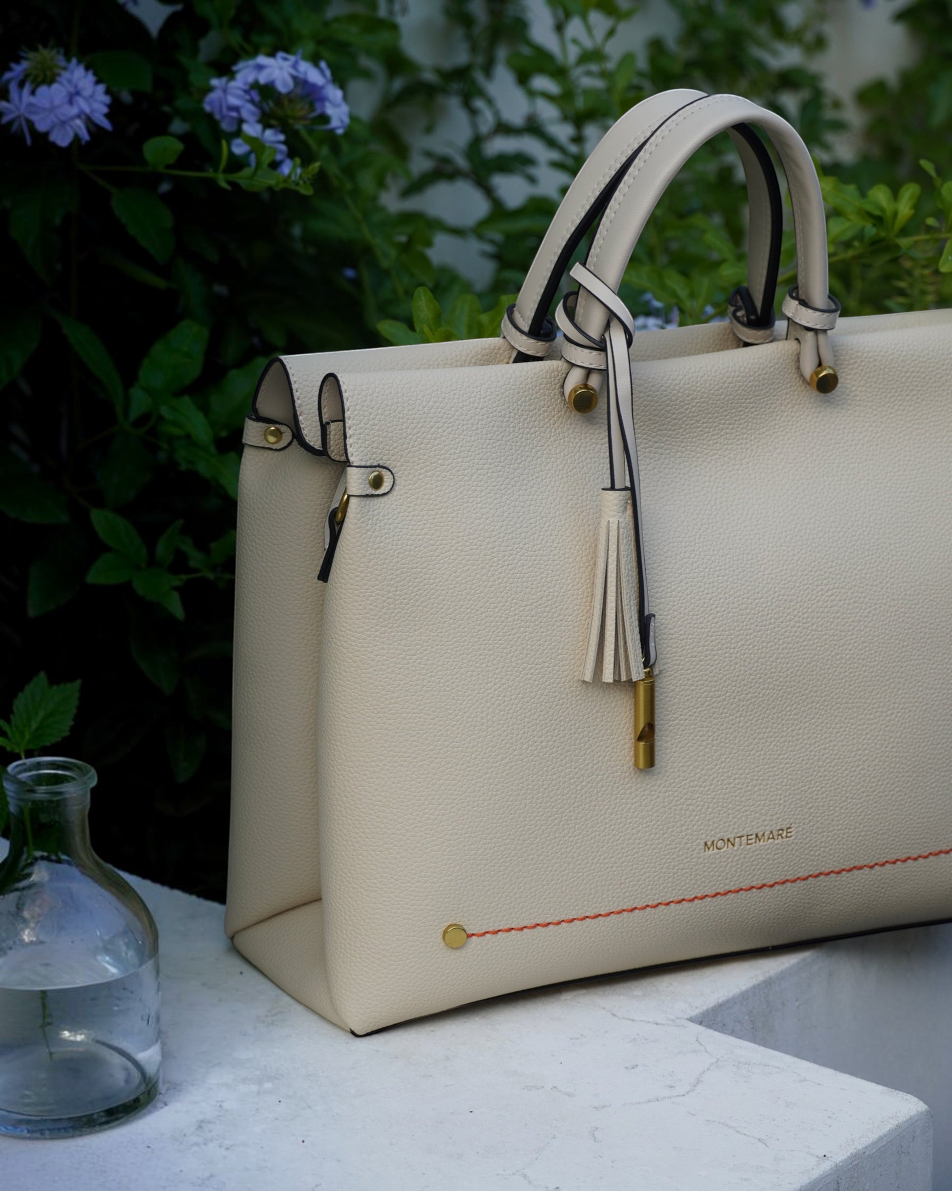 Montemaré Vienna small cream vegan leather carry-on tote with a safety whistle tassel and orange accent stitching