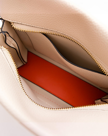 Interior of Montemaré Vienna Crossbody bag showing beige pebbled vegan leather and a bright orange lining.
