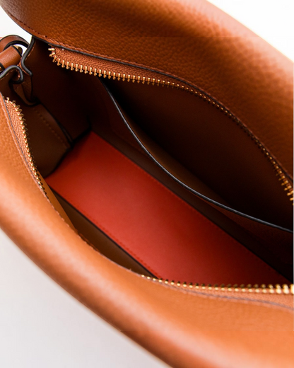 Interior view of the Montemaré Vienna Crossbody bag featuring pebbled brown vegan leather and a bright orange base.