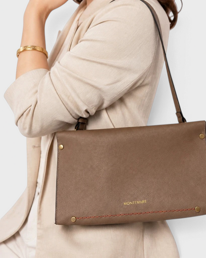 Montemaré Vienna small shoulder bag in taupe pebbled vegan leather with a shoulder strap worn by a woman.
