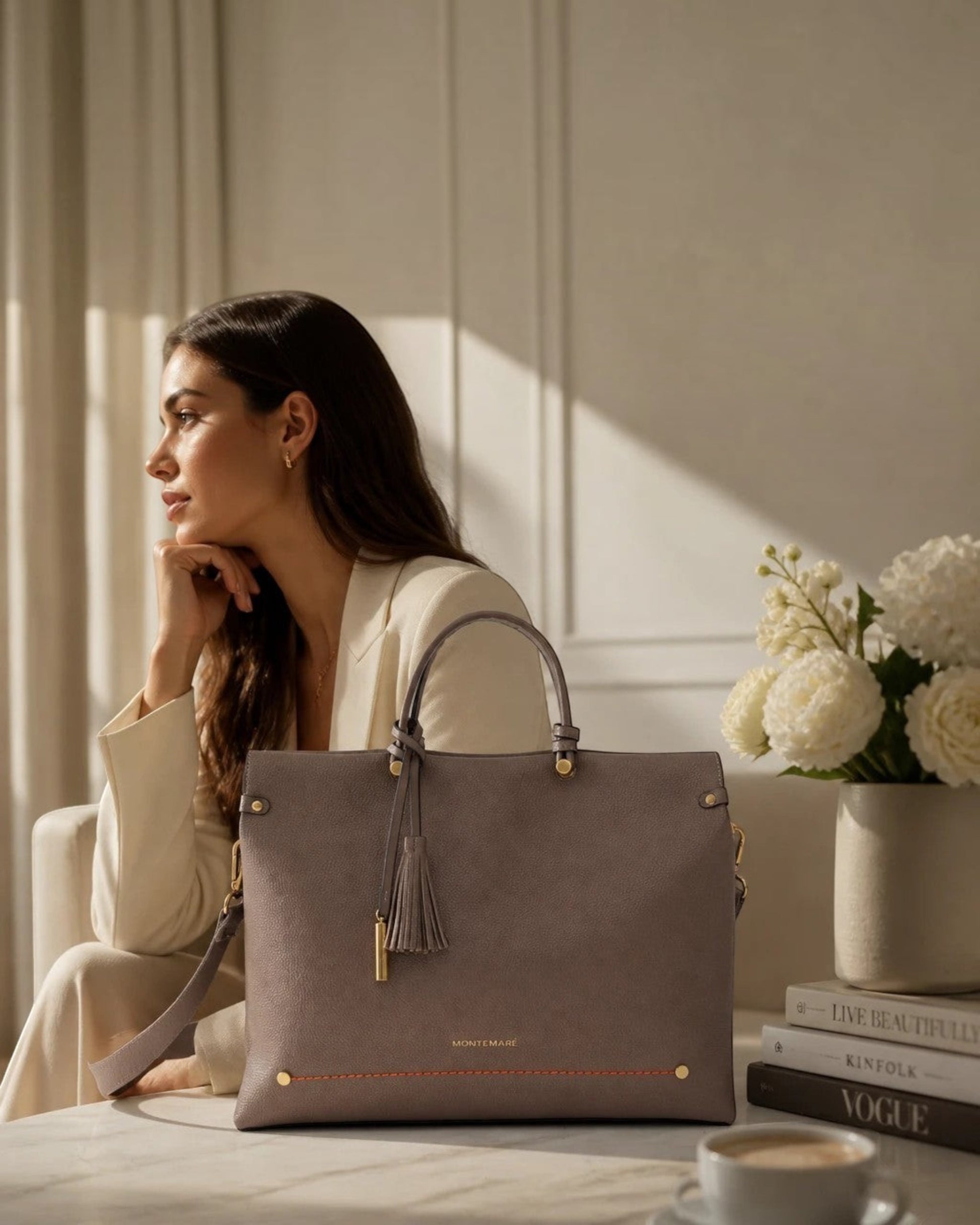 Montemaré Vienna small carry-on tote in taupe vegan leather with a safety whistle tassel, sitting on a table.