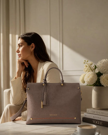 Montemaré Vienna small carry-on tote in taupe vegan leather with a safety whistle tassel, sitting on a table.