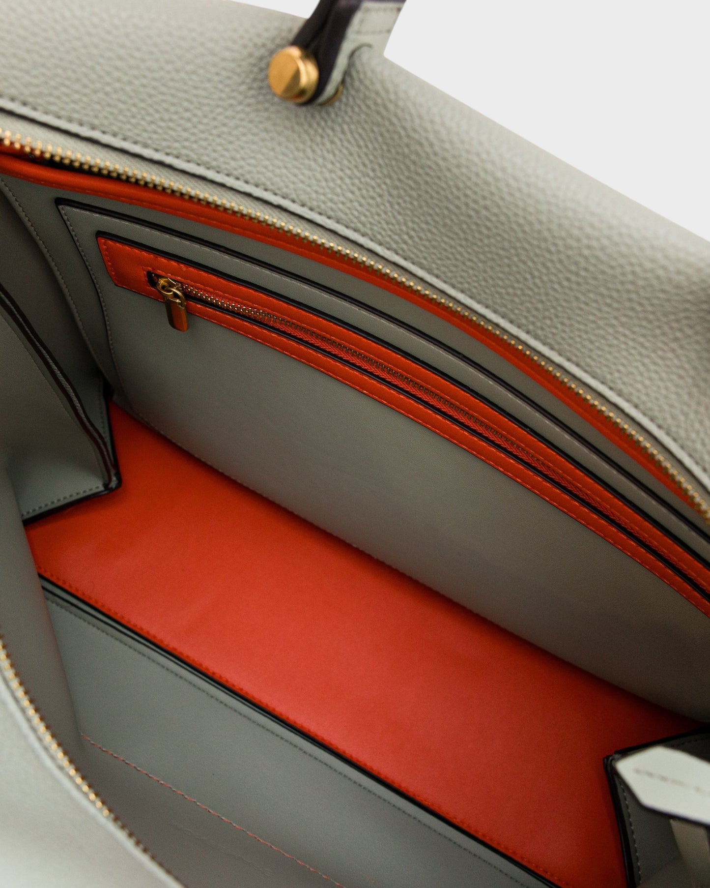 Interior of Montemaré Vienna Small Carry-On Tote in sage green vegan leather with a vibrant orange zippered pocket